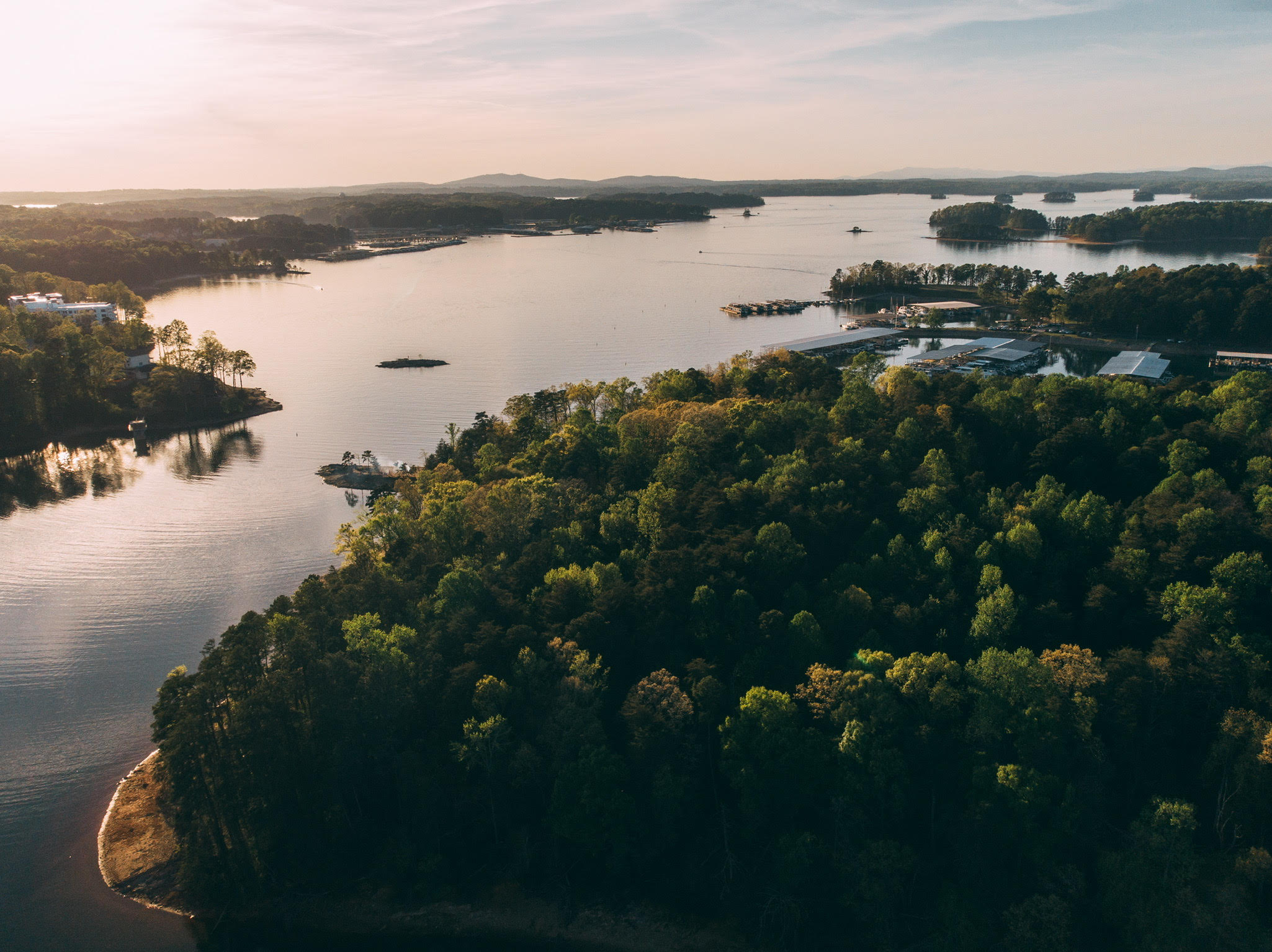 Golden-hour aerial view of a North Georgia lake and wooded shoreline